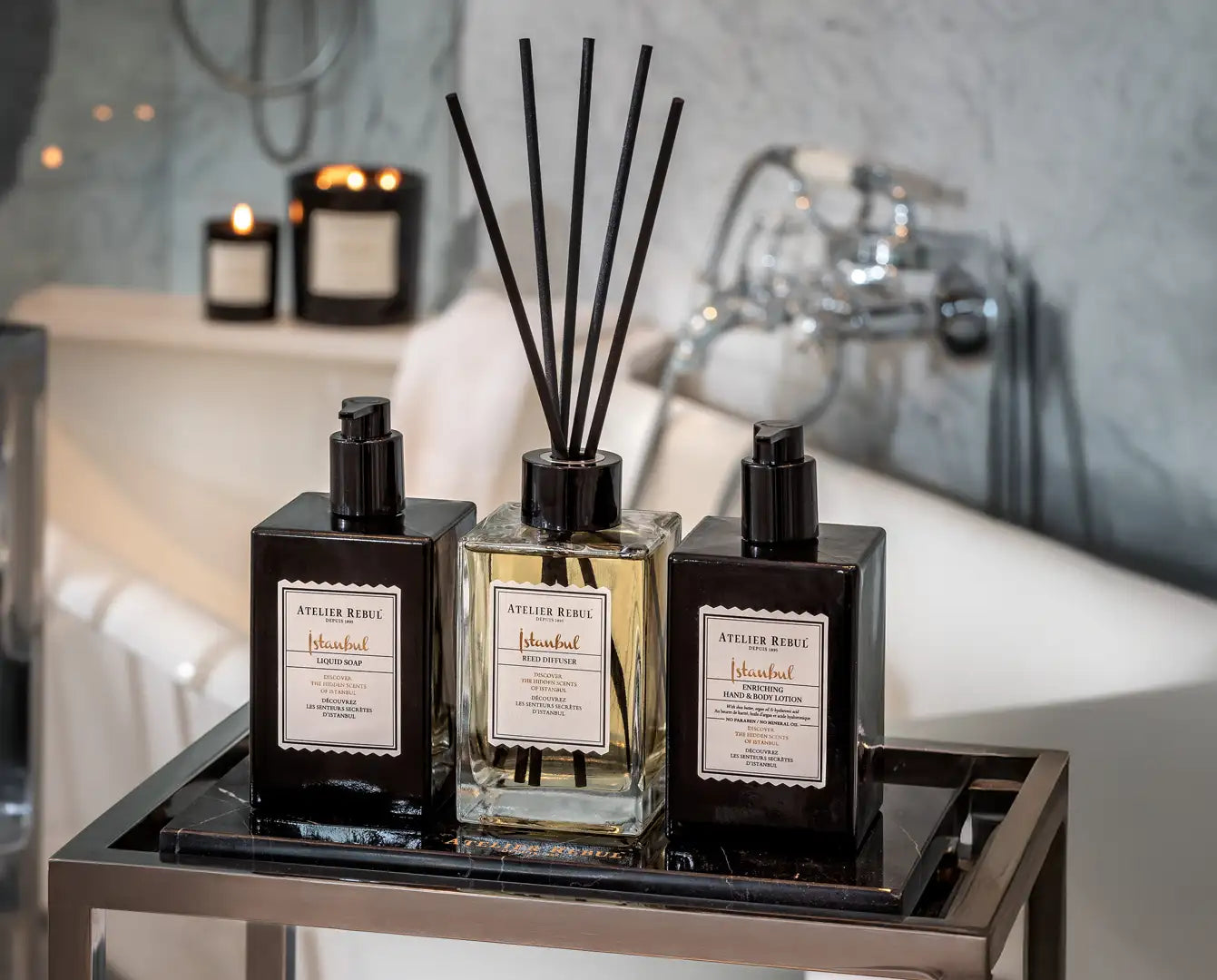 Trei difuzoare elegante atelier reine, cu sticle negre cu pompă elegante și un difuzor central din sticlă cu lichid auriu.