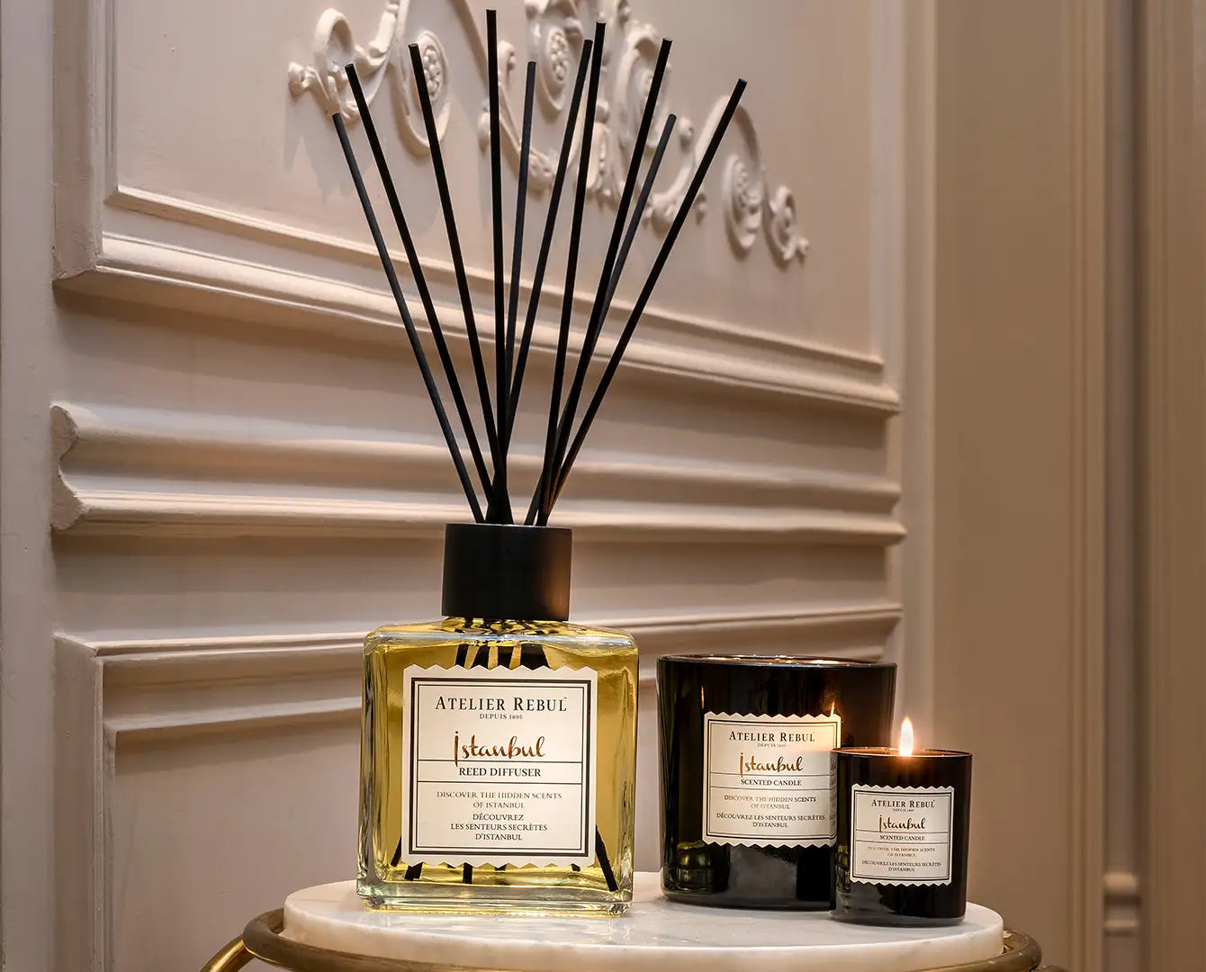 Difuzor elegant de stuf cu stuf negru și lichid auriu, etichetat „atelier rebel istanbul” într-un design minimalist.