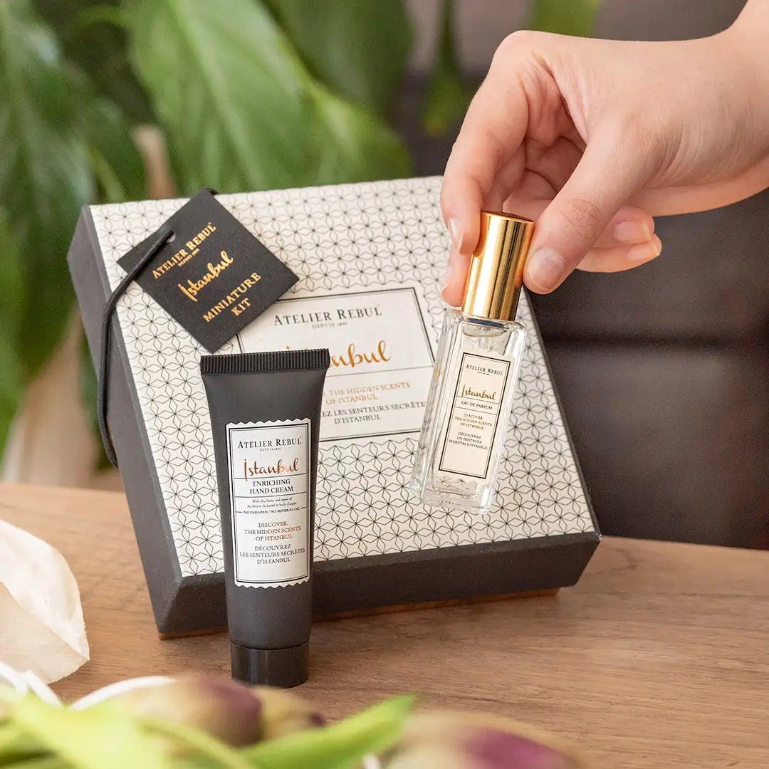 Sticlă de parfum cu capac auriu, etichetă albă și ambalaj cutie cu model geometric