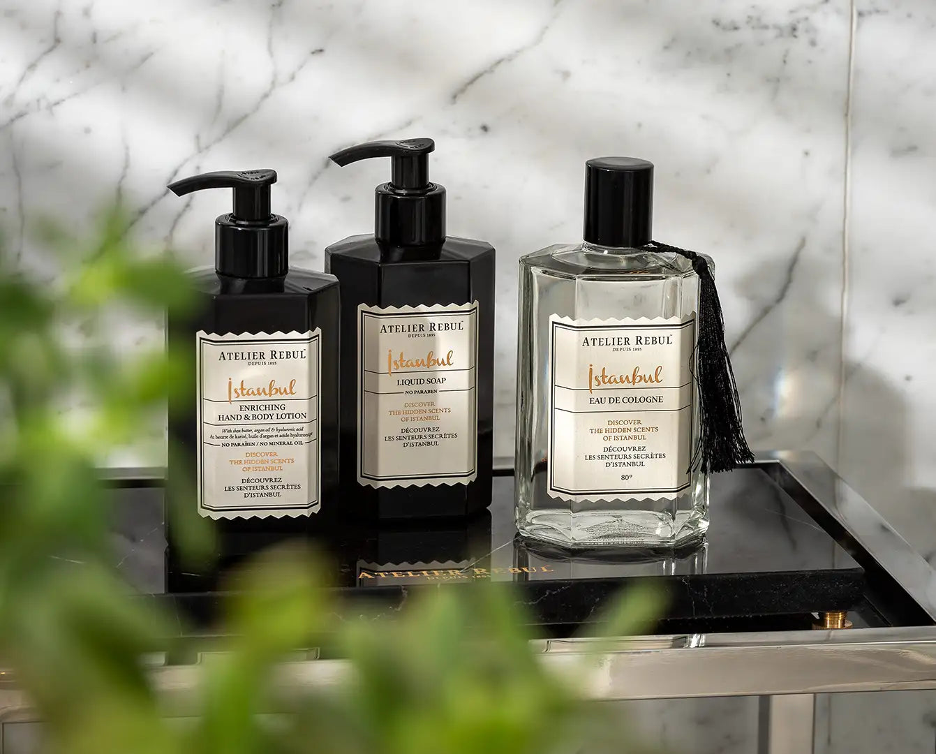 Sticle negre cu pompă de la atelier rebul istanbul cu loțiune pentru mâini și corp, săpun lichid și eau de cologne cu litere elegante aurii pe etichete albe.